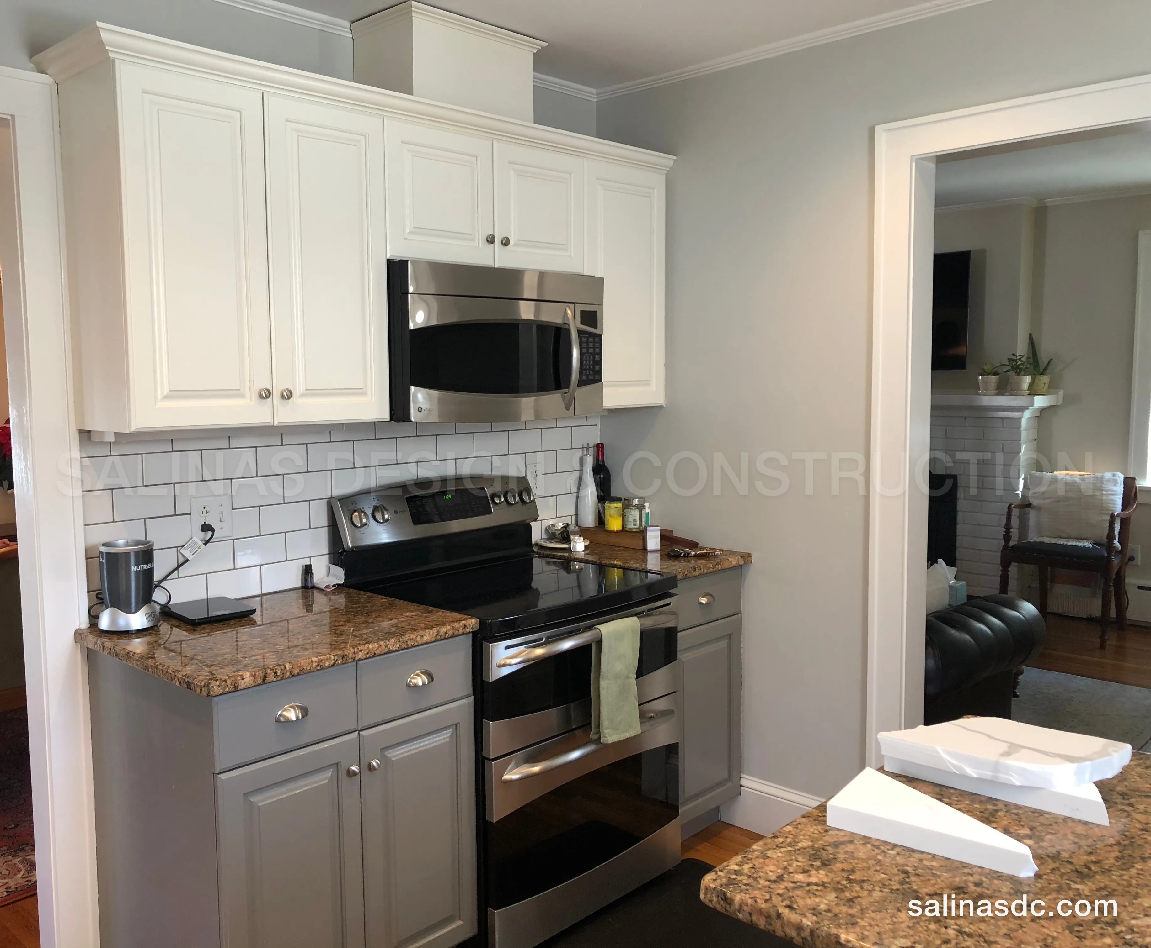 The Norwalk kitchen before the remodel: cream raised panel cabinets, a wall microwave and brown granite counters