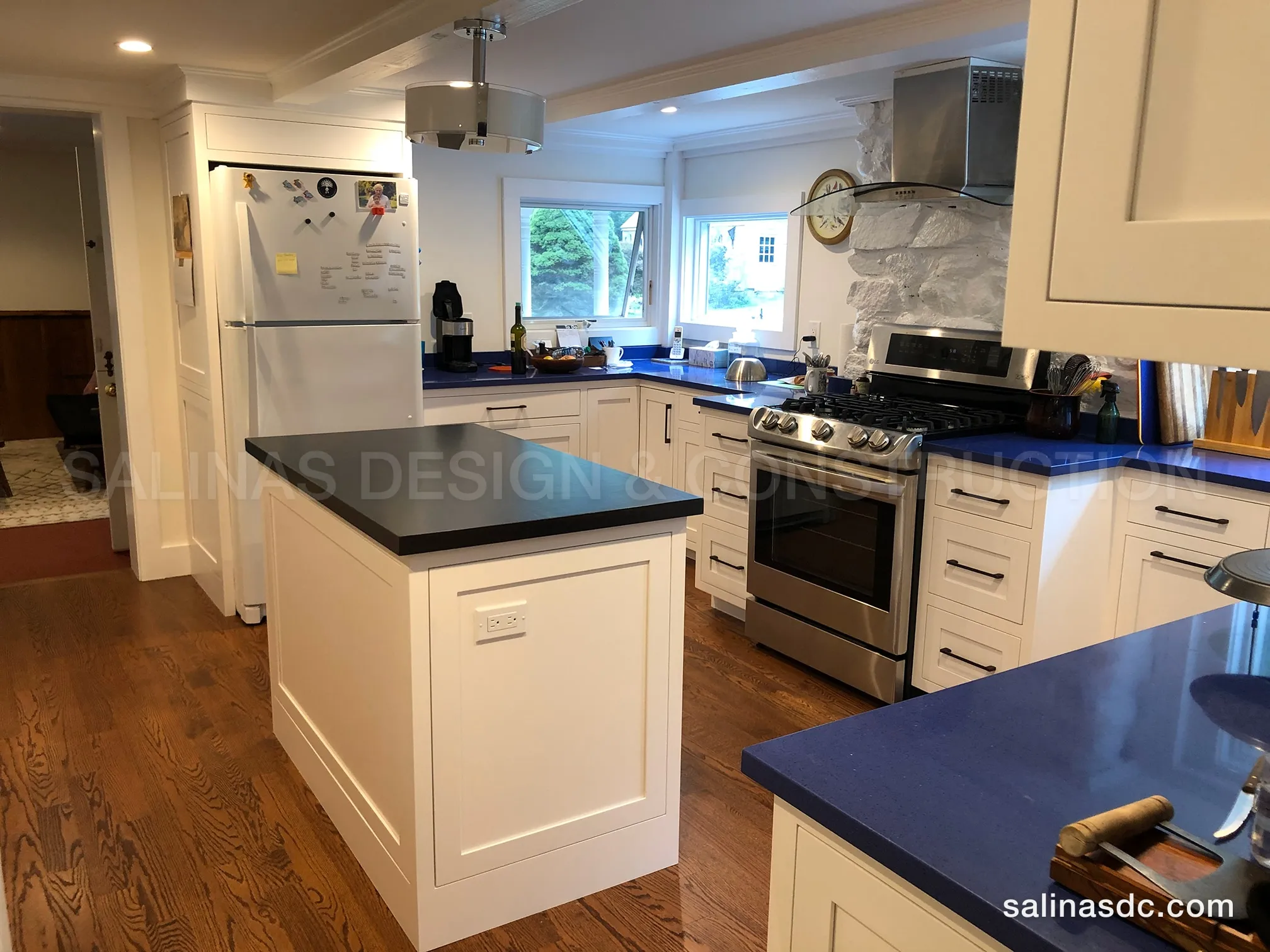 Finished kitchen remodel in Redding, Connecticut: white shaker cabinetry, a painted island with a dark stone top and a stainless range under a stone backsplash